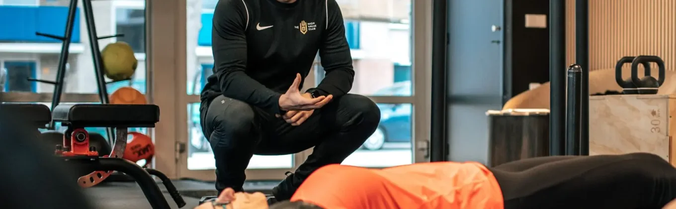 Een coach begeleidt een lid tijdens de training