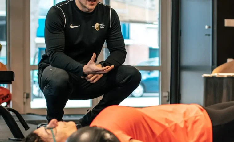 Een coach begeleidt een lid tijdens de training